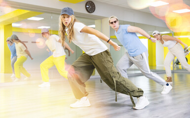 Group of cool, active teenage dancers having fun and learning new dance exercise movement in studio