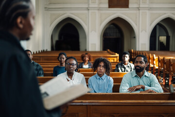 Priest holding bible giving sermon to congregation in church