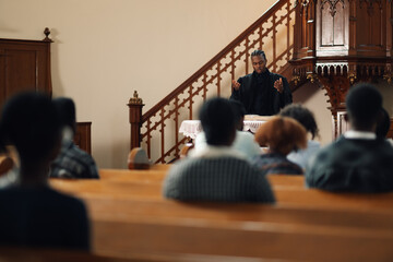 Young pastor preaching in front of congregation at church