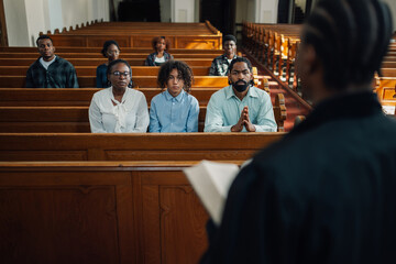 Preacher speaking to congregation members sitting in church pews