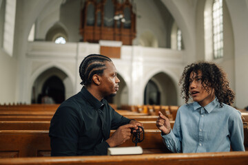 Priest listening to young man talking about problems in church