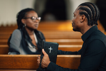 Priest holding bible during church service listening to woman