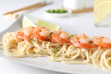 Delicious pasta with shrimps, green onions and lime on white table, closeup