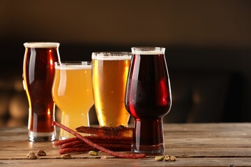 Glasses with different types of beer and snacks on wooden table indoors