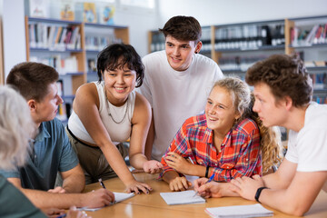 Fototapeta premium Group portrait of smiling young teenage children working together in public library