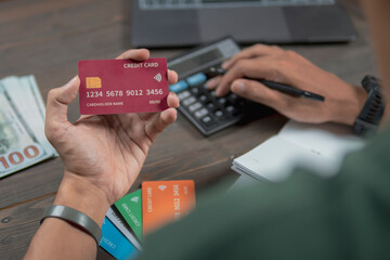 Showing a Man holding a credit card and using a calculator, the concept of accounts and savings.