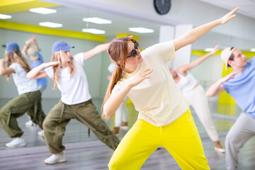 Active young girl with sunglasses practicing breakdance Toprock moves in training hall. Teenagers engaged in breakdance