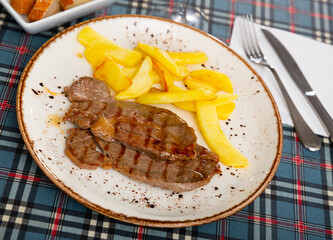 Beef and potato served on table with serving pieces and bread