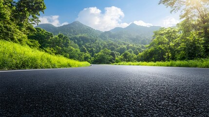 Scenic asphalt road winding through lush green mountains and dense forests under a clear blue sky