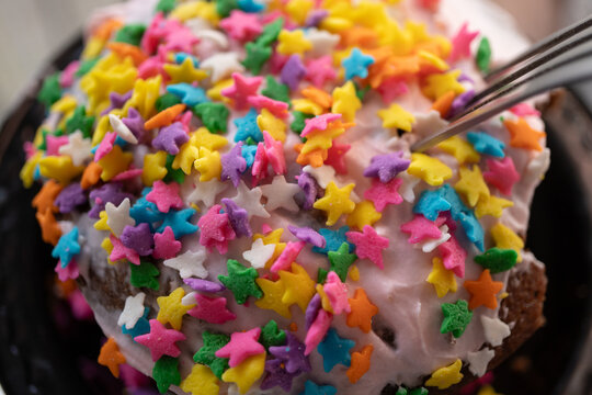 Estrellitas de az&uacute;car decorando pastel peque&ntilde;o de chocolate con tenedor