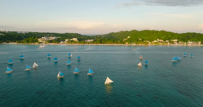 Tropical white beach with sunset. Boracay with hotels and paraw sailing boats. Philippines.