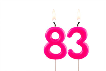 Pink number 83 birthday candle lit on white background
