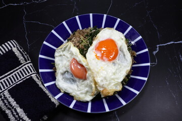 Fried spicy minced pork rice topping with fresh and organic chicken egg yolk serving on the plate. Famous special street food menu in Asia. 