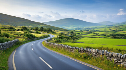 Naklejka premium A winding road through the Irish countryside, bordered by stone walls and vibrant green fields, leading towards distant hills under a soft blue sky, tranquil and inviting mood