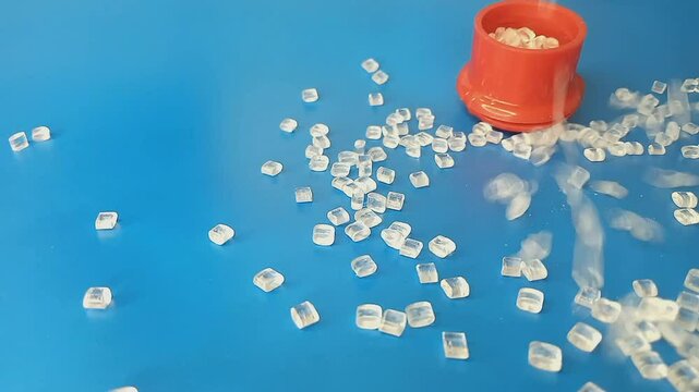 virgin polymer granules, falling like flowing water splashing into a mound, isolated on blue background, for industrial plastic product profile video