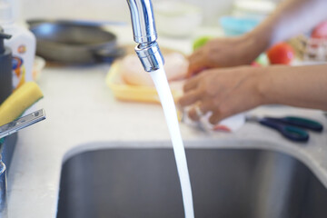 A CloseUp View of Water Flowing from a Kitchen Faucet with Sunlight Streaming In