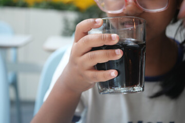 A Child Happily Enjoying a Refreshing Cold Drink While Sitting in a Cozy Cafe Setting