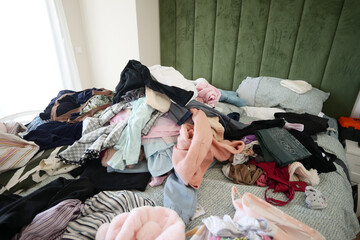 A Messy Bed with Various Colorful Clothes and Soft Pillows Is a Cozy and Casual Space