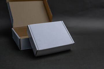 Fototapeta premium A white box is sitting on top of a brown box The white box is slightly open The white box is sitting on a black surface