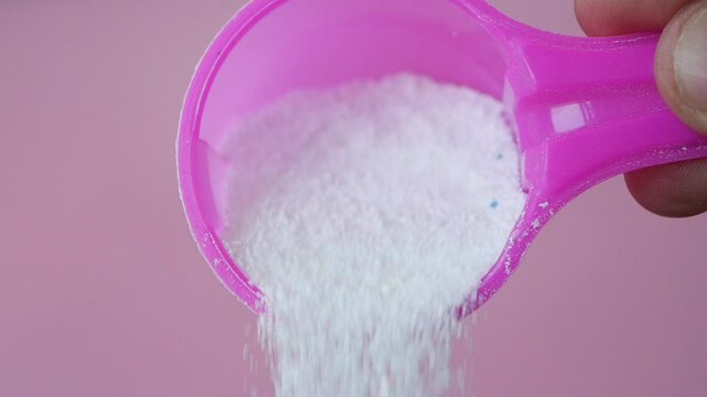 Washing powder pouring from a plastic spoon 