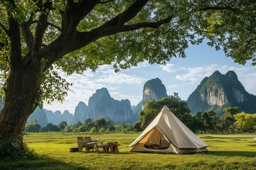 Camping tent on the grass under big trees. See the scenery of limestone mountains.