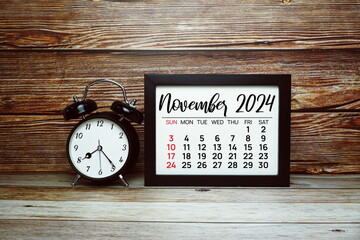 NOVEMBER 2024 monthly calendar for planning and management concept with alarm clock on wooden...