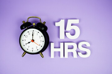 15 Hrs alphabet letters and alarm clock top view on purple background