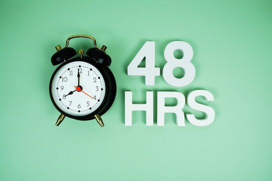 48 Hrs alphabet letters and alarm clock top view on green background