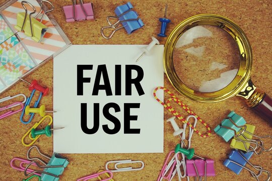 Fair Use text on paper card with magnifying glass and stationery on cork board background