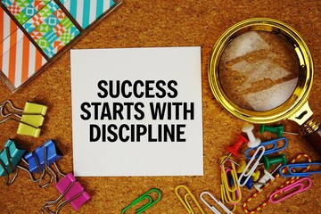 Success Starts With Discipline text on paper card with magnifying glass and stationery on cork board background