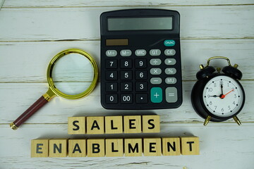 Sales Enablment with wooden blocks alphabet letters and magnifying glass, calculator, alarm clock...