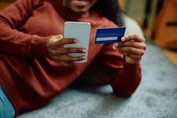 Close up of black woman m-banking at home.