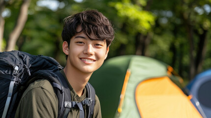 young man with backpack smiles warmly in camping setting, surrounded by tents and greenery, embodying spirit of adventure and outdoor exploration