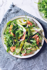 Healthy salad with arugula, smoked salmon, pear, avocado and red onion