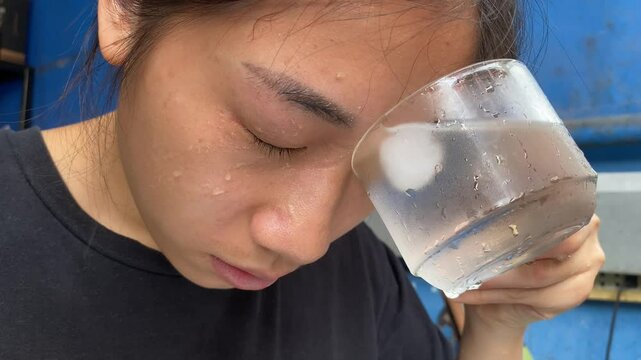 Asian woman wash eye irritation in glass of cold water. Cleaning eye concept 