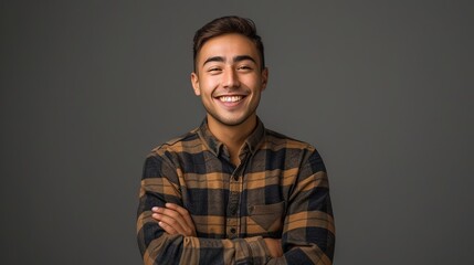 Obraz premium Joyful smiling young man with folded arms, cheerful portrait photography in studio setting on gray background, confident and happy male model