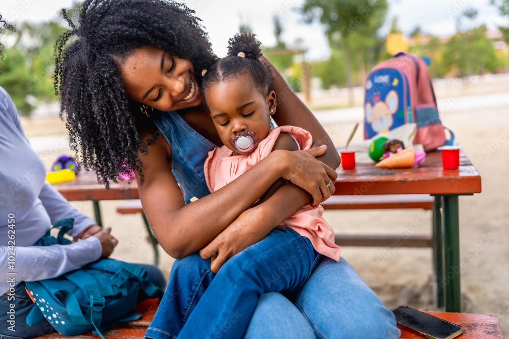 Wall mural happy african woman embracing her baby daughter in the park