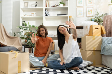 Two asian Women Waving hand and Smiling Amidst Moving Boxes