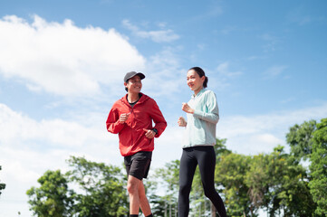 A young Asian couple wearing blue and red sportswear, the two of them jogging together. Ready to...