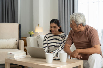 Asian senior couple use laptop working in living room