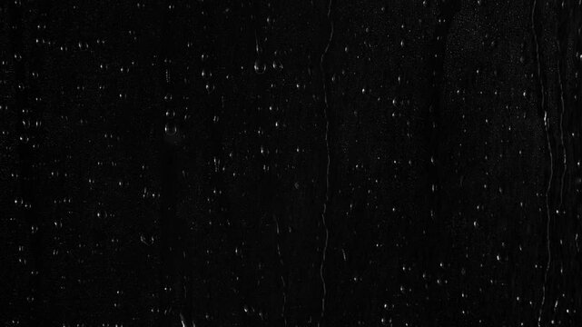 Closeup water rainfall, rain drops falling on window glass over black background