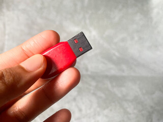 Red USB flash drive in woman's hand with grey color background. 