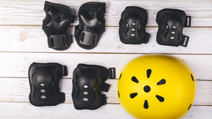 Yellow helmet, knee and hand protection. Concept set of protection for roller skating, cycling and...