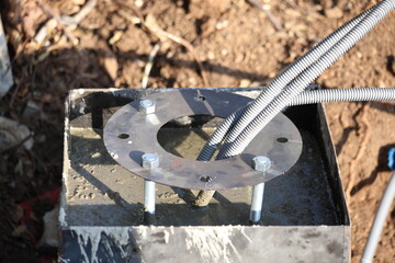 The foundation of a street lamp. Cement base with nuts and bolts.