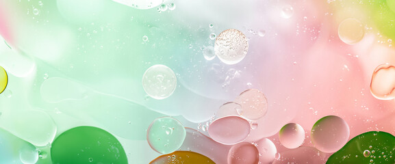 Abstract macro image of oil and water bubbles on a pastel pink and green gradient background,...