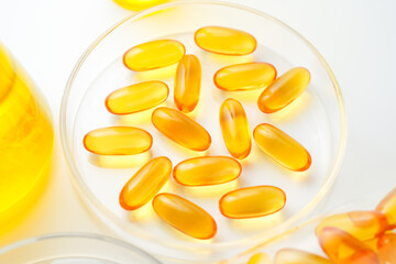 Petri dish with fish oil capsules inside, vitamin D, omega softgels, supplements, keto diet.