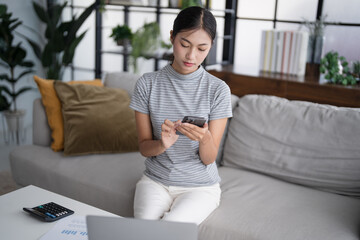 Obraz premium Asian woman holding paper document calculating money savings paying bills in mobile application using smart phone payment online with paying household bills tax insurance managing budget