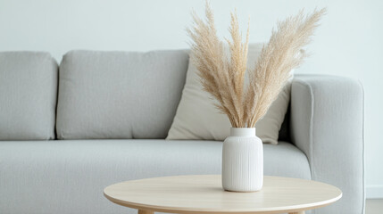 A stylish living room featuring light gray sofa and wooden coffee table adorned with white vase filled with dried pampas grass, creating serene and modern atmosphere