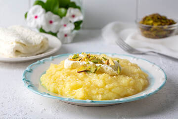 Sweet yellow Turkish dessert cheese halva Hosmerim on the white plate in the kitchen.