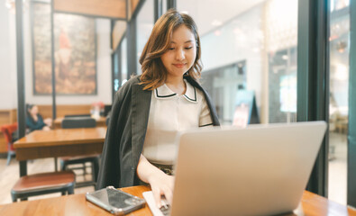 Obraz premium Business freelance asian woman using smartphone and laptop computer at cafe urban lifestyle